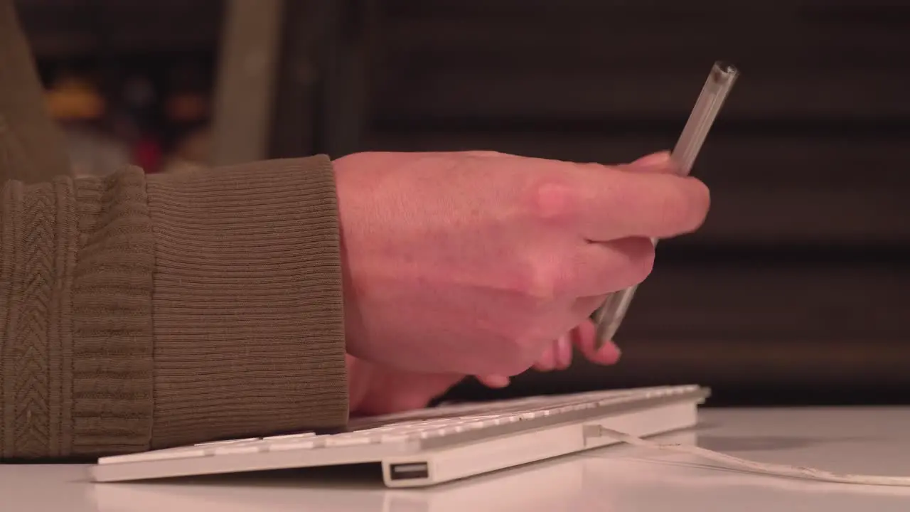 Nervous hand spins pen in fingers while other writes on computer keyboard