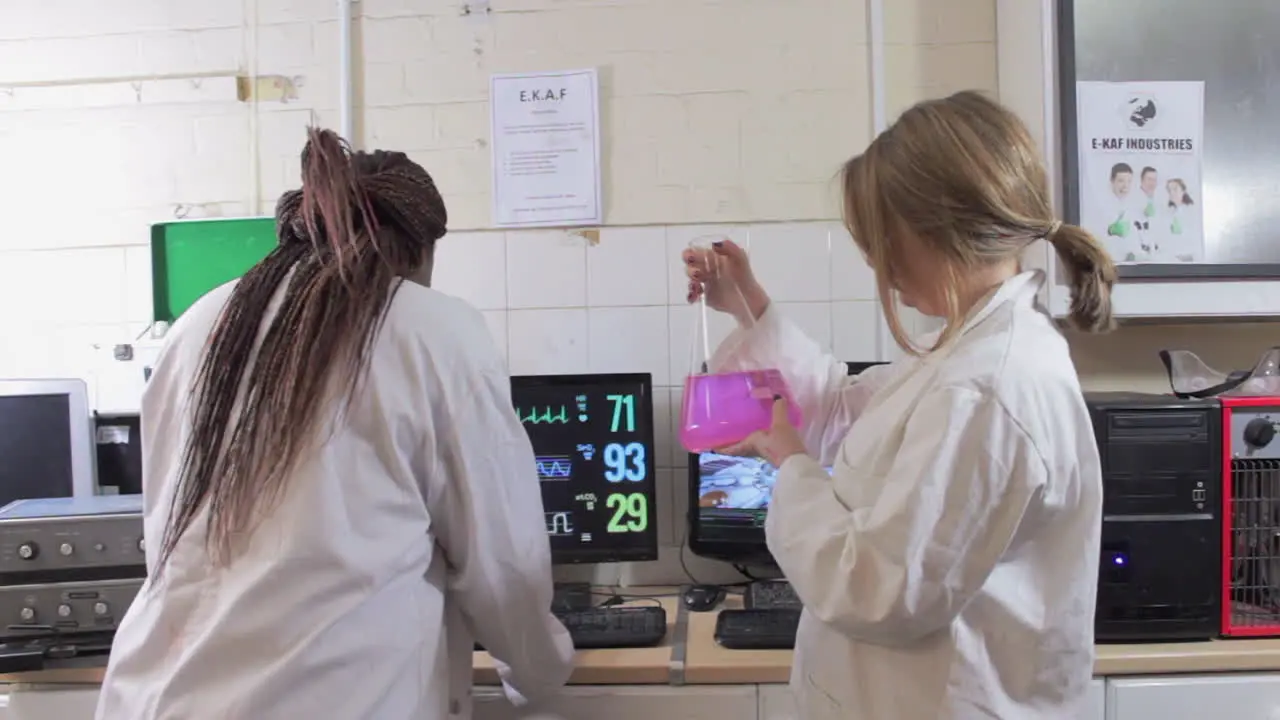 Two Female Scientists Are Working With Liquids and computers In A Laboratory