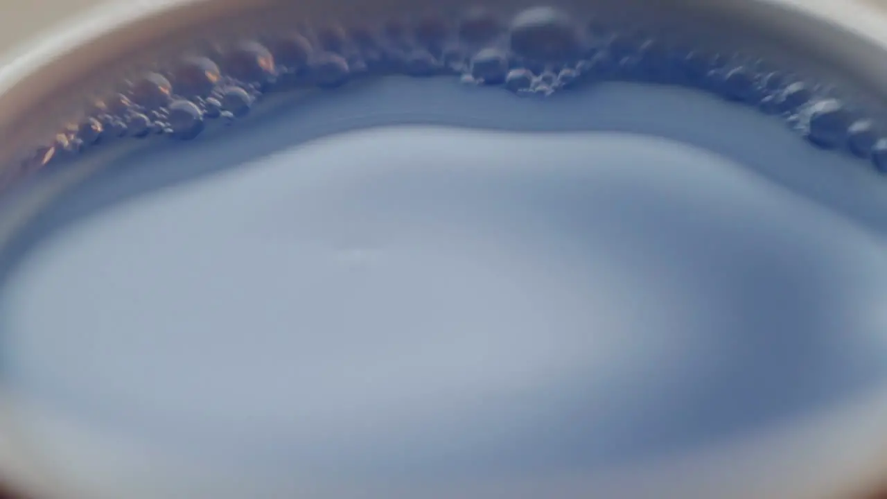 Water droplets falling into blue coloured water