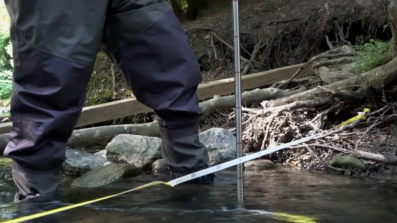 A scientist measures the flow of a Swiss river using a probe and a meter