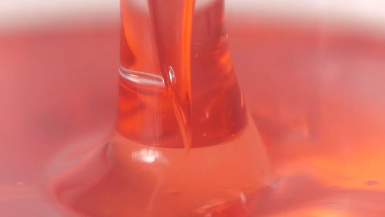 Red liquid is being spilled in laboratory macro close up view