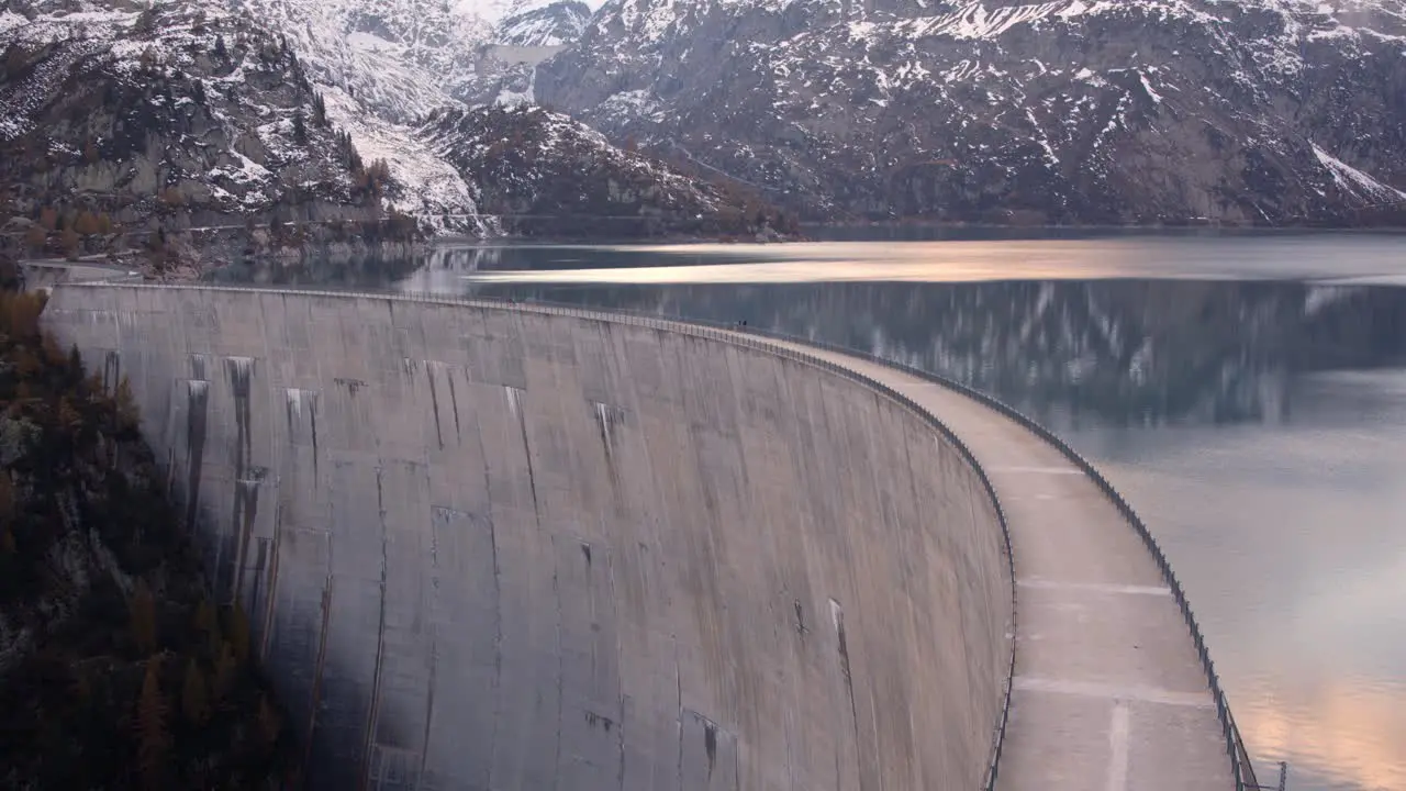 Massive dam in a mountain lake at sunset