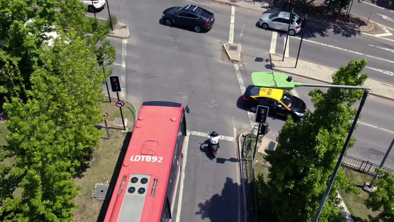 A Red Bus Waits in Santiago de Chile Streets Traffic Lights Aerial Drone Taxi and Cars Drive along Las Condes Neighborhood