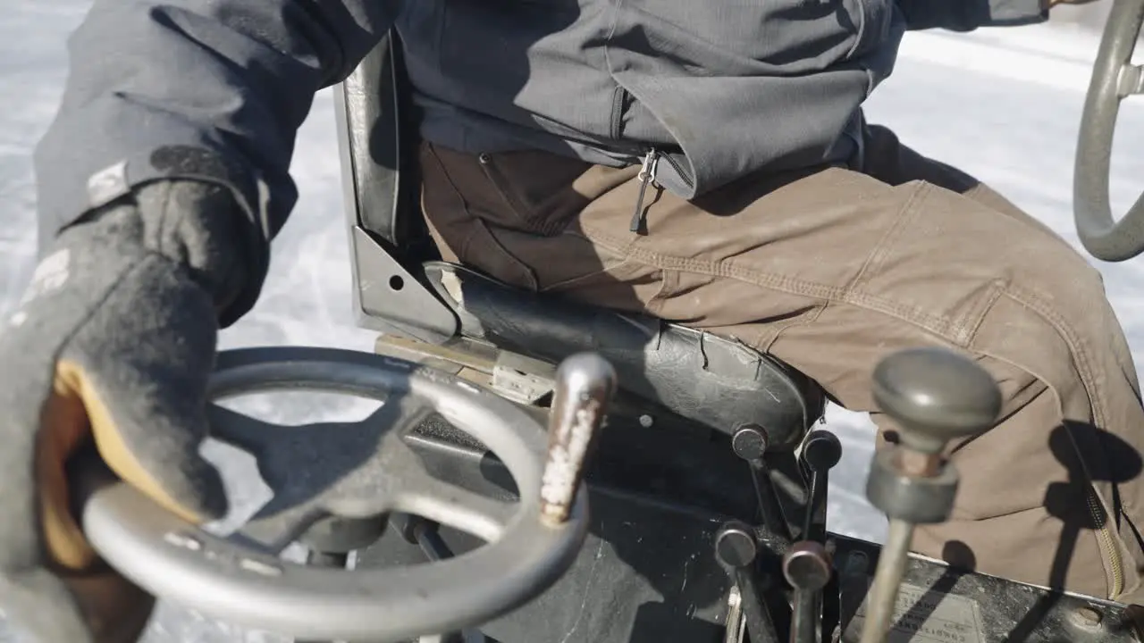 Zamboni driver turning wheel on ice resurfacer machine outdoors