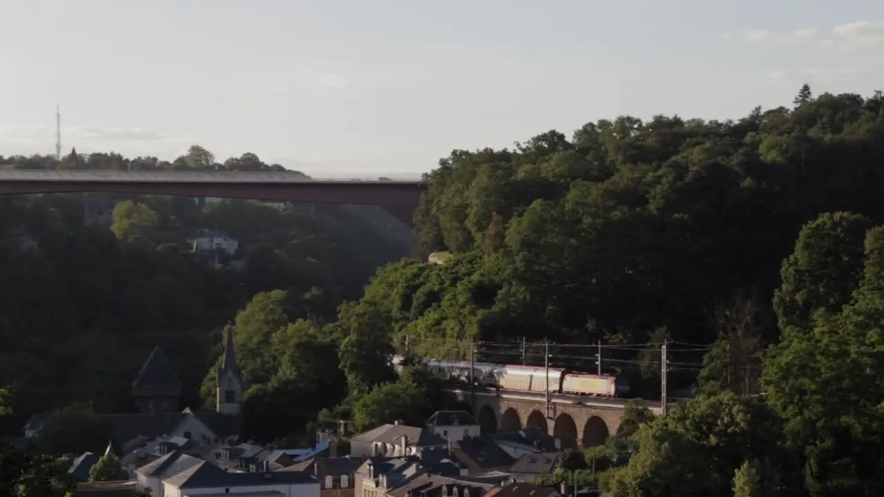 Train driving along the Kirchberg Plateau through the Alzette Valley in Luxembourg City at sunset on a summer day