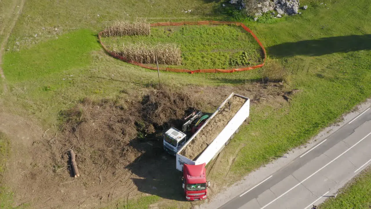 Aerial wide top shot of a man arranging his truck's load full of woodchips