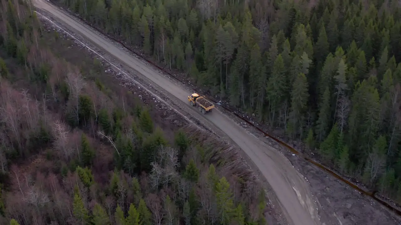 Articulated truck driving through a dirt road in the middle of the forest with cargo from a construction site heavy equipment