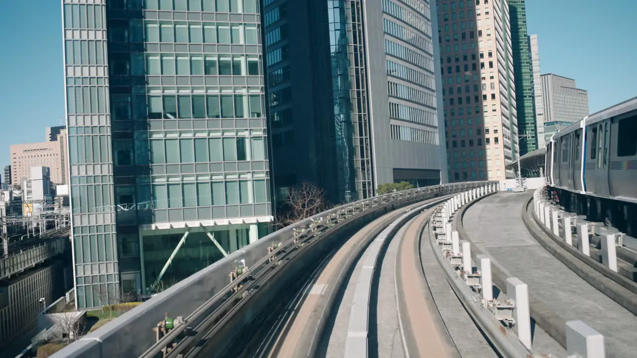 A point-of-view shot of a Yurikamome monorail arriving at a station with skyscrapers in the background in Tokyo Japan