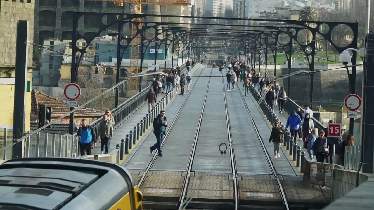 Establishing shot Metro Tram Train Passing by the station at Don Luis I Bridge in Porto Portugal People walking around in the background