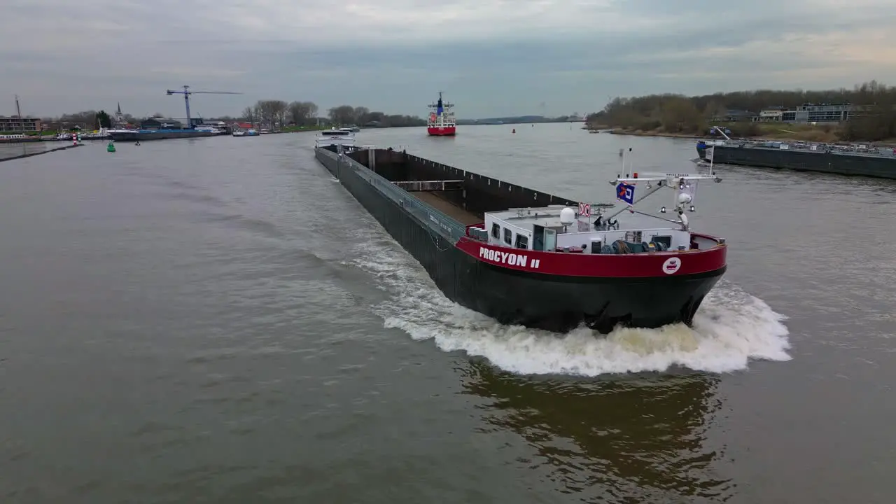 Empty cargo ship Procyon 2 navigating fast through the inland canal aerial view