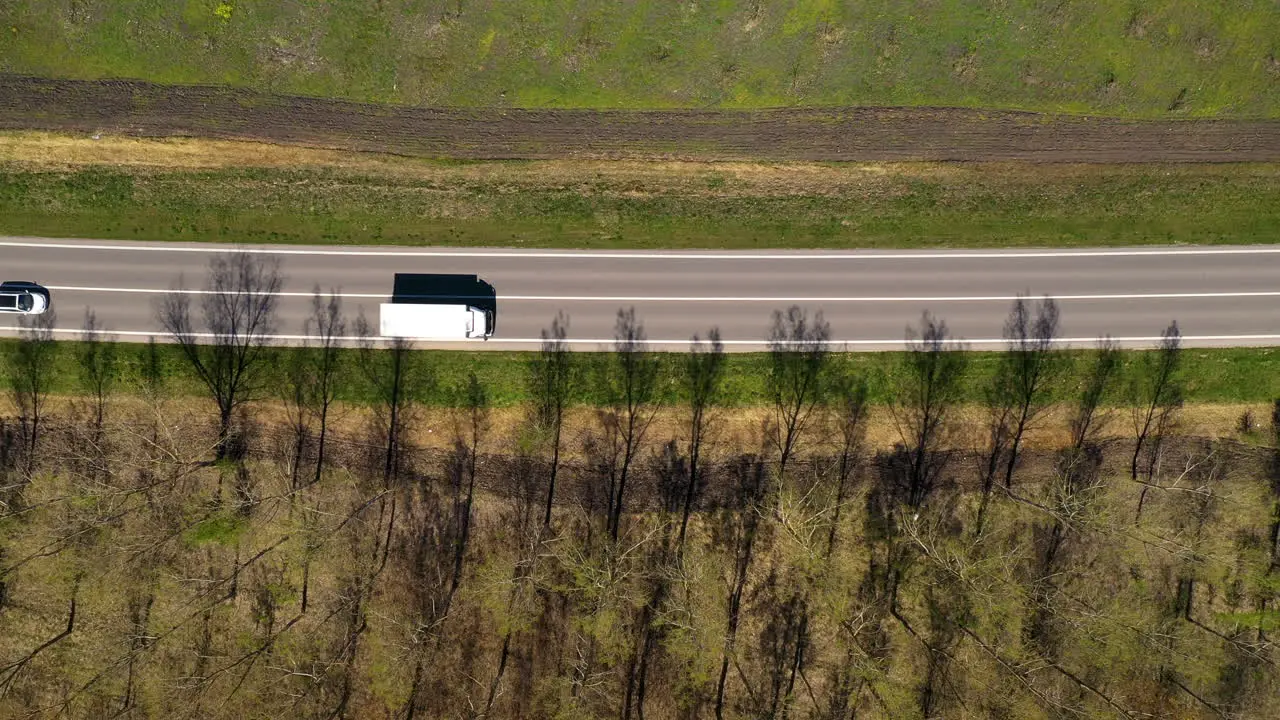 Aerial shot of traffic on highway through wooded landscape drone pov