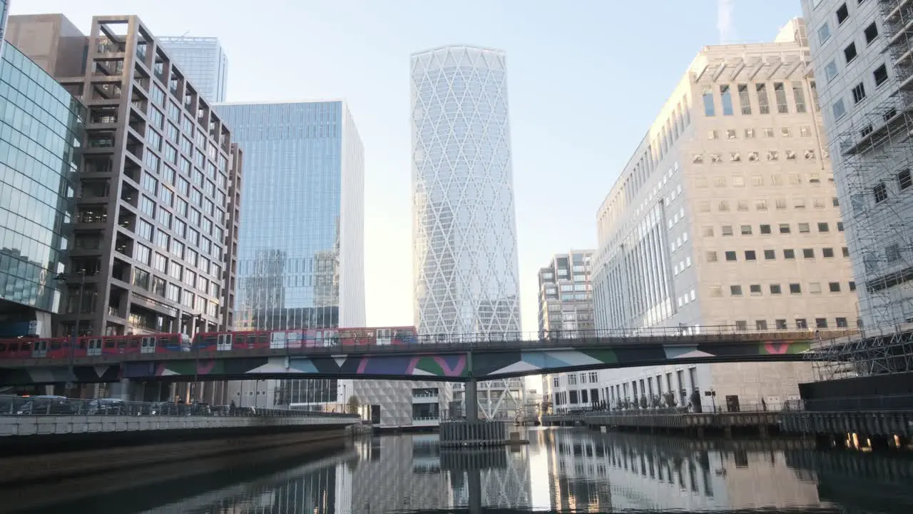 Red London DLR train passing over bridge behind Newfoundland building Canary wharf London