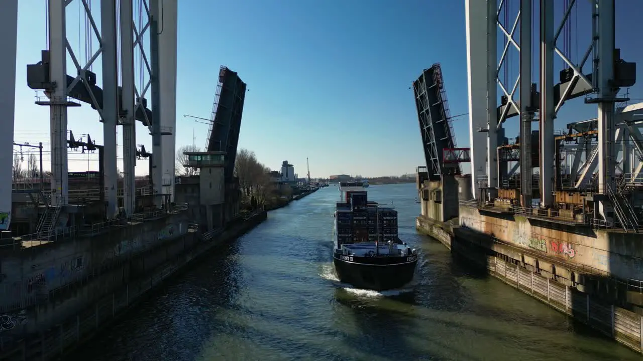 Cargo ship fully loaded with containers navigating through the drawbridge