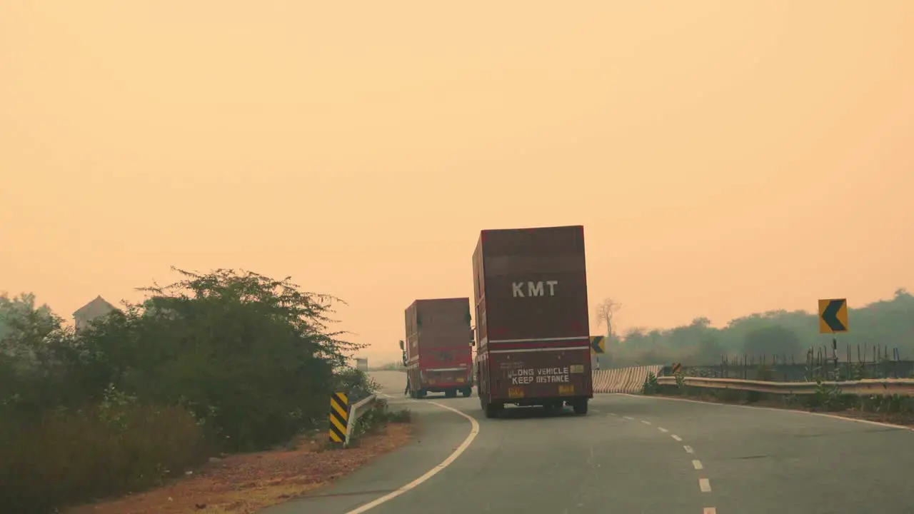 Cargo truck with cargo trailer driving on a highway through forest and hills during morning time in India