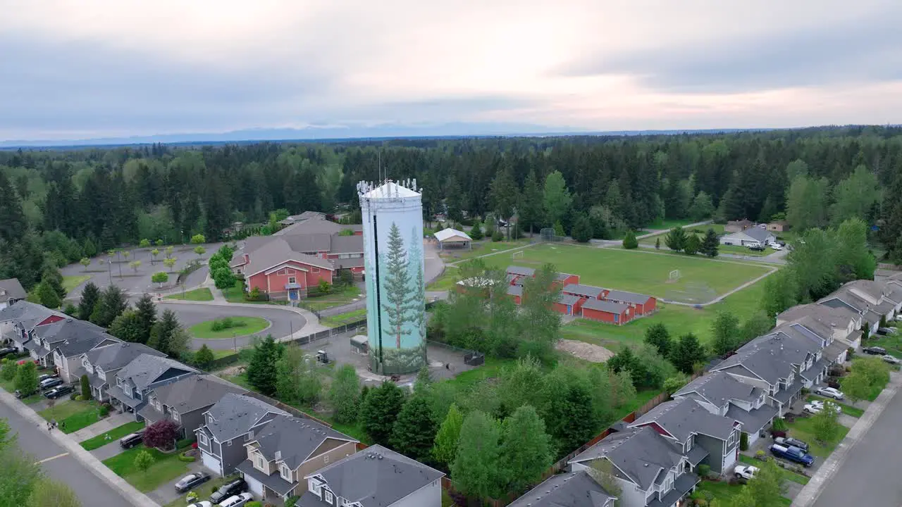 Orbiting aerial shot around a suburban water tower with an elementary school in the background