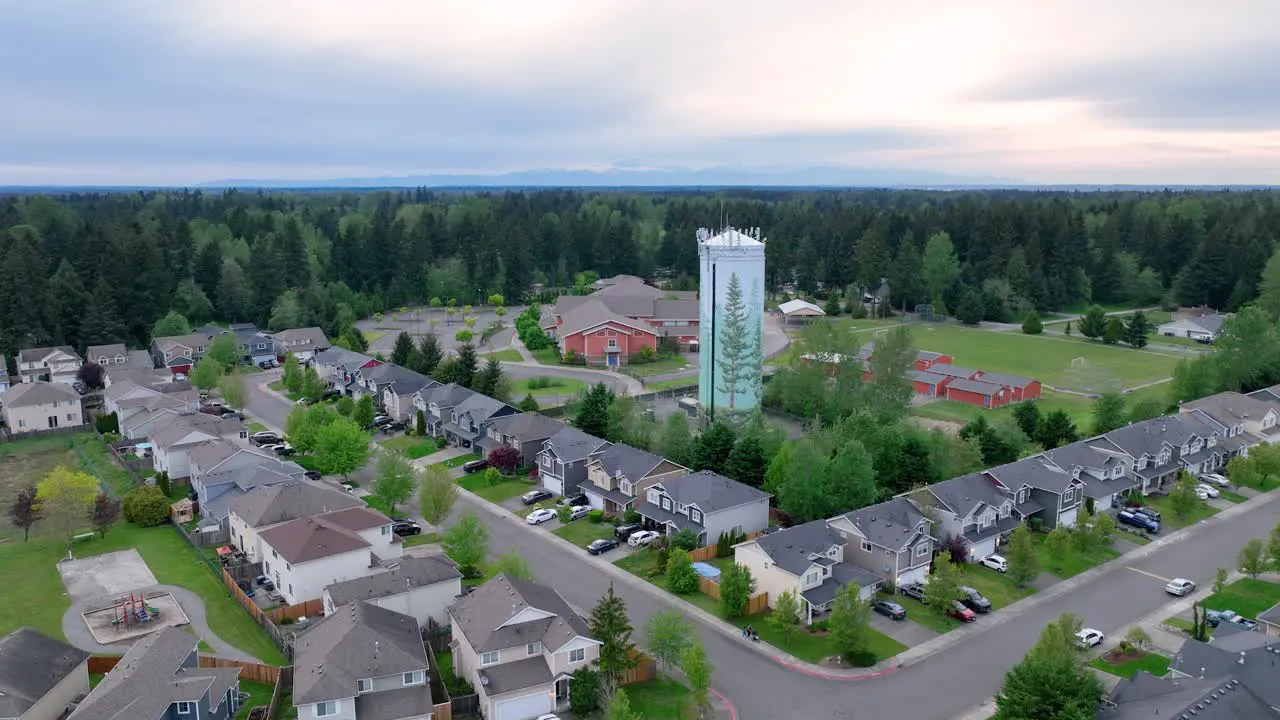 Orbiting aerial shot around a suburban water tower with a neighborhood in the foreground