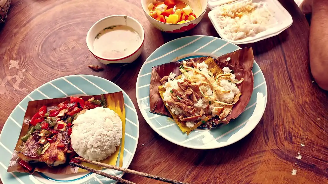 Overhead view of eating authentic traditional khmer food for breakfast of Trei boeng kanh chhet or spicy fried fish and Bai sach chrouk or pork with steamed rice