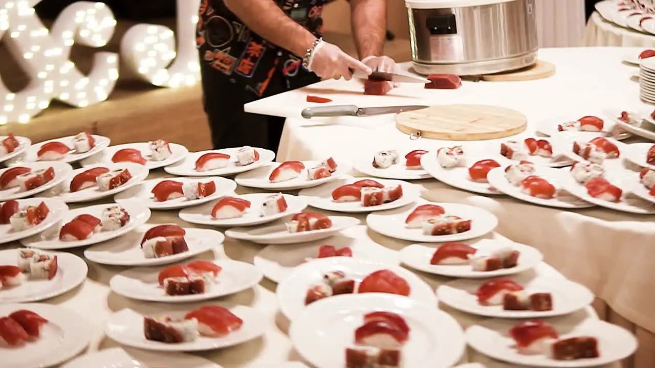 Profesional chef cutting and preparing sushi rolls plates for a wedding banquet