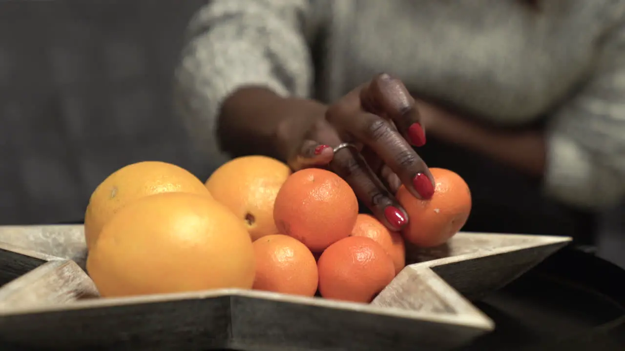 Black woman picking mandarin oranges from a bowl