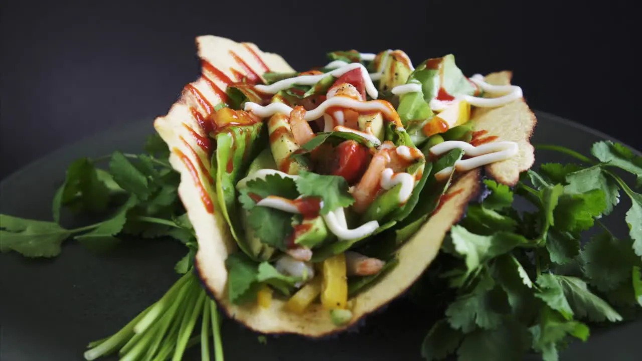 Freshly Prepared Shrimp Taco rotating on black background with raw cilantro 4k