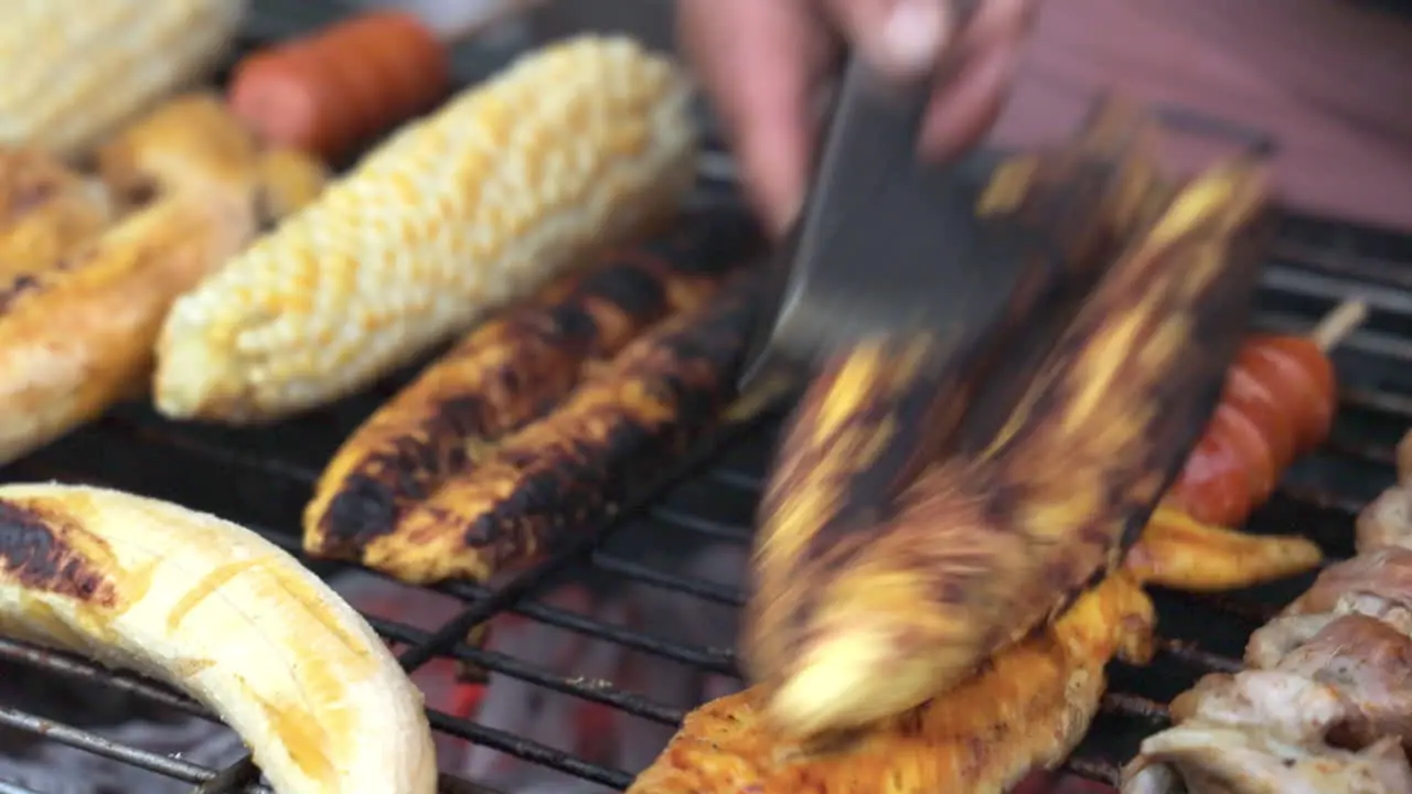 Close Up View Of Vendor Slicing Charcoaled Banana On Grill Beside Corn Cob For Customer In San Cristobel In The Galapagos