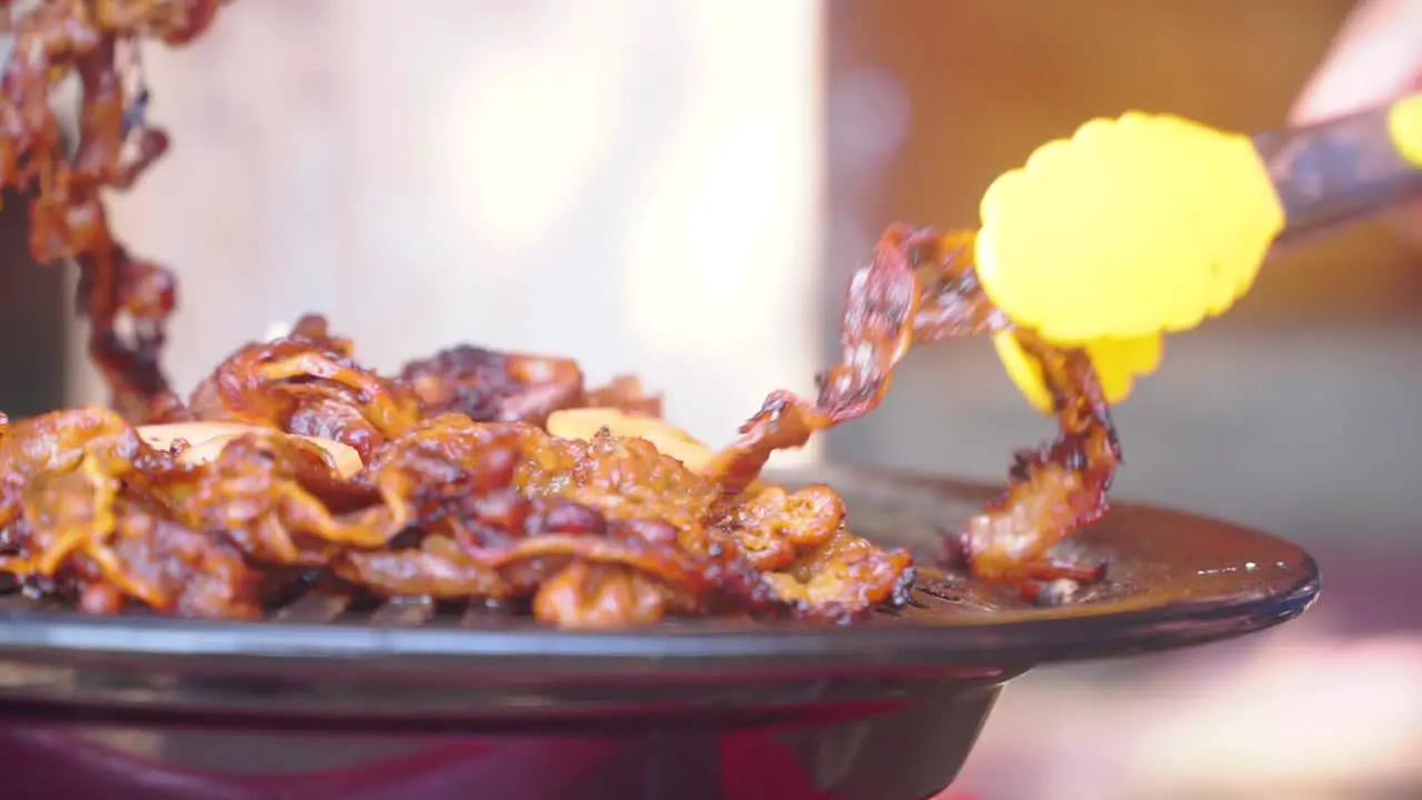 Closeup shot of cooking barbeque meat grilled on grill pan using food tongs