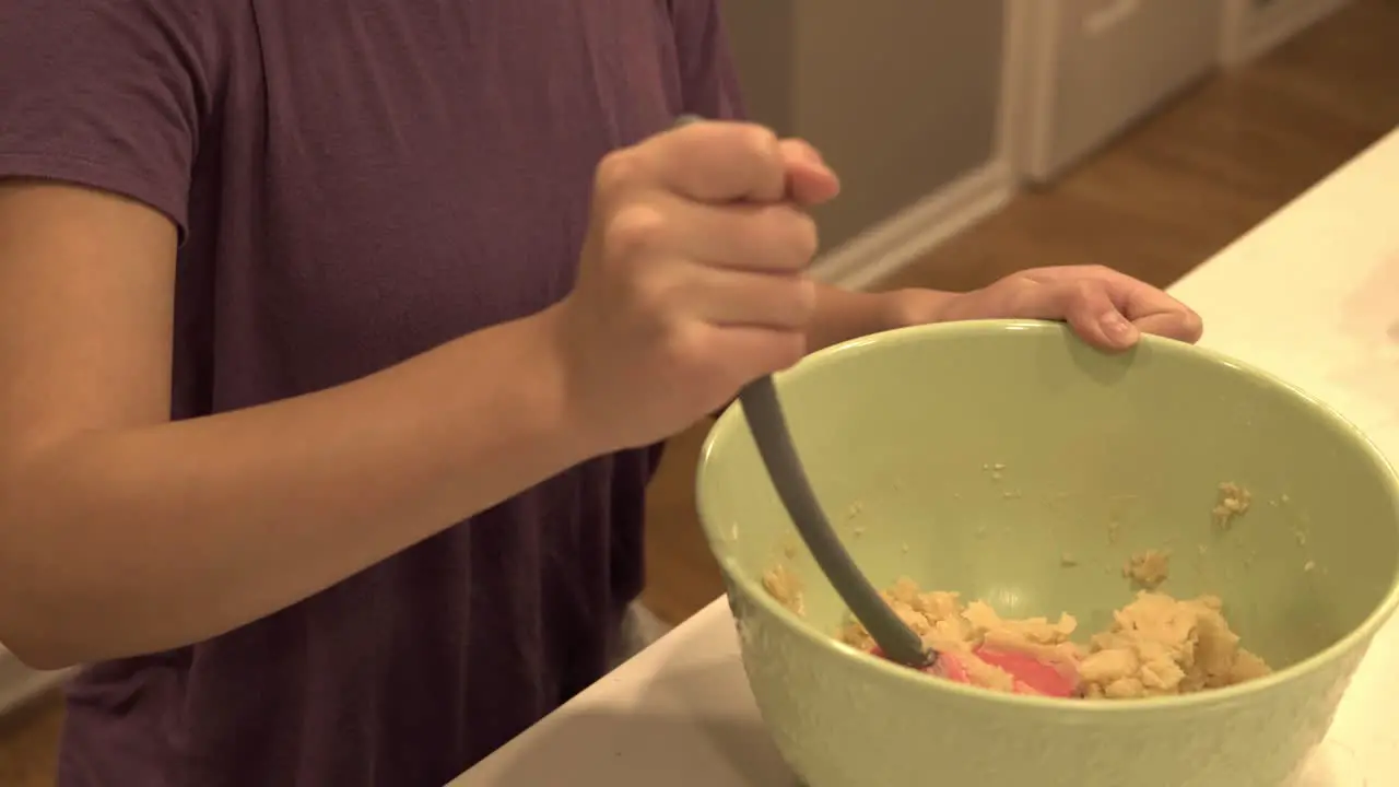 A young Korean girl mixes contents in a large bowl while making millionaire shortbread cookies