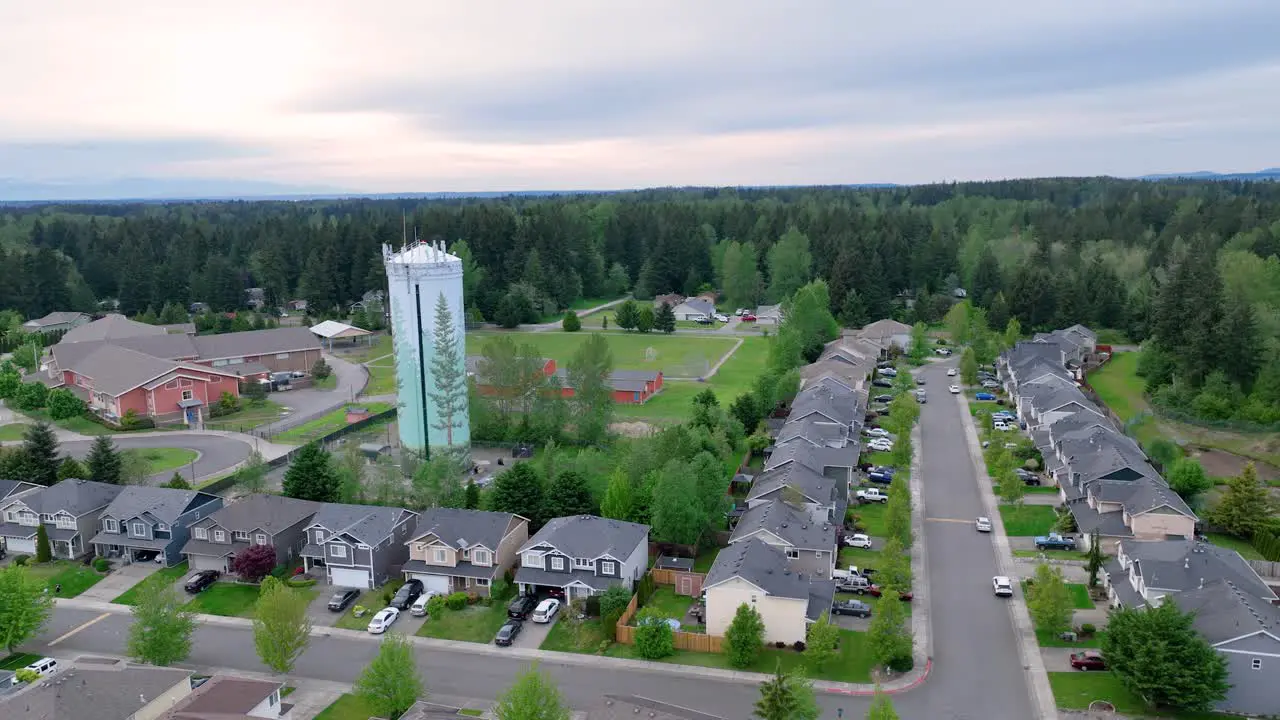 Orbiting drone shot around a suburban water tower with an elementary school in the background