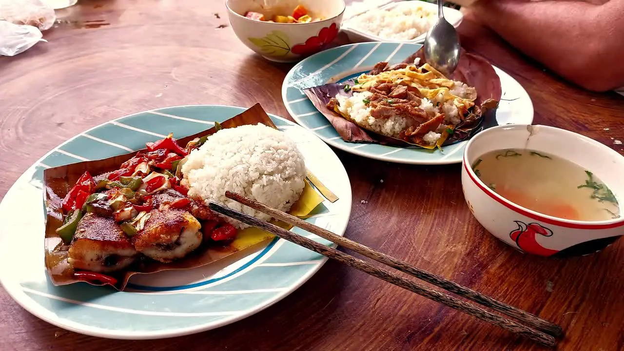 Eating authentic traditional khmer food for breakfast of Trei boeng kanh chhet or spicy fried fish and Bai sach chrouk or pork with steamed rice