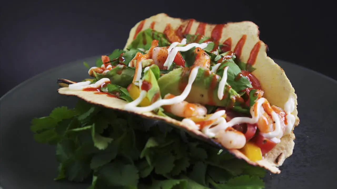 Freshly Prepared Shrimp Taco rotating on black background with trimmed cilantro 4k