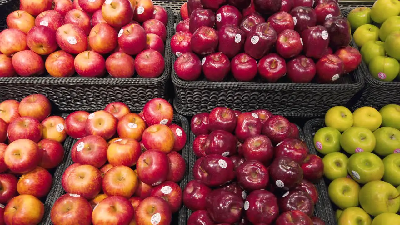 Panning camera over the fruit shelf stall in supermarket with many kind of apples on stall