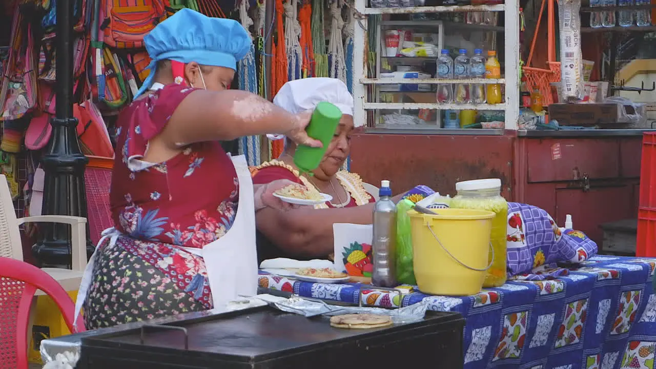 Two women provide tasty street food at grill cart in Leon Nicaragua