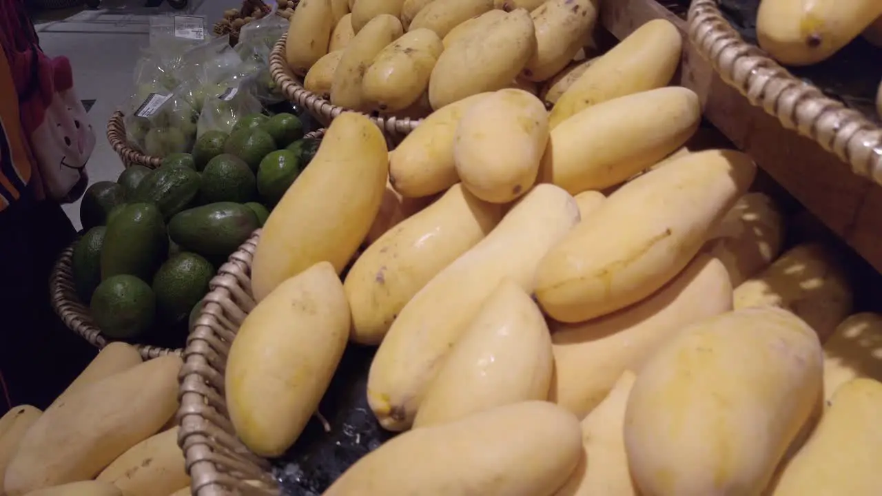 Panning camera over the fruit shelf stall in supermarket with many kind of mangoes on stall