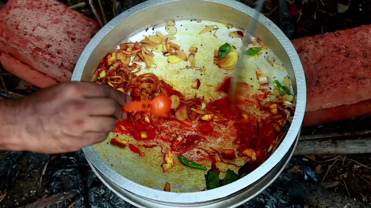 Onions ginger garlic and curry leaves are added and chilli powder is added to the mix  black clam masala curry traditional outdoor black clams cooking pollution  masala  brick