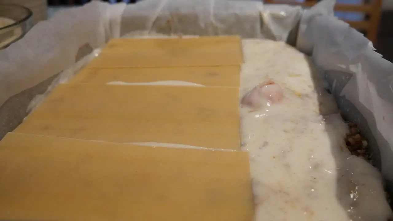 lasagne assembly putting pasta sheets on top of bechamel sauce