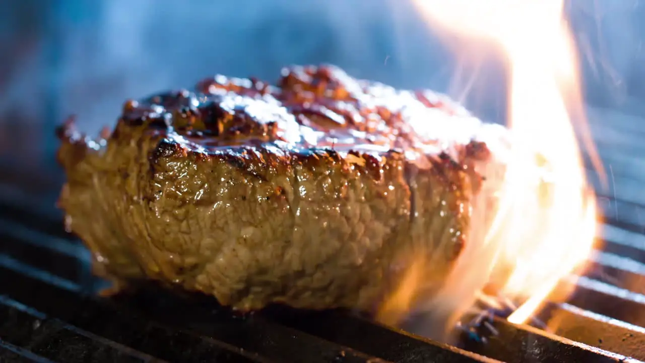 Grilling steak on a fire grill with flames 4K