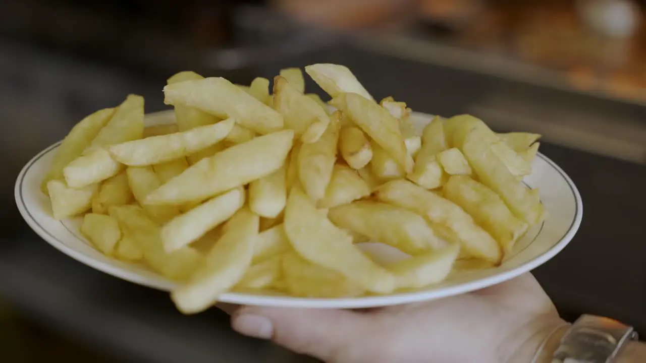 Person Holding French Fries Plate Ready To Be served For Customers