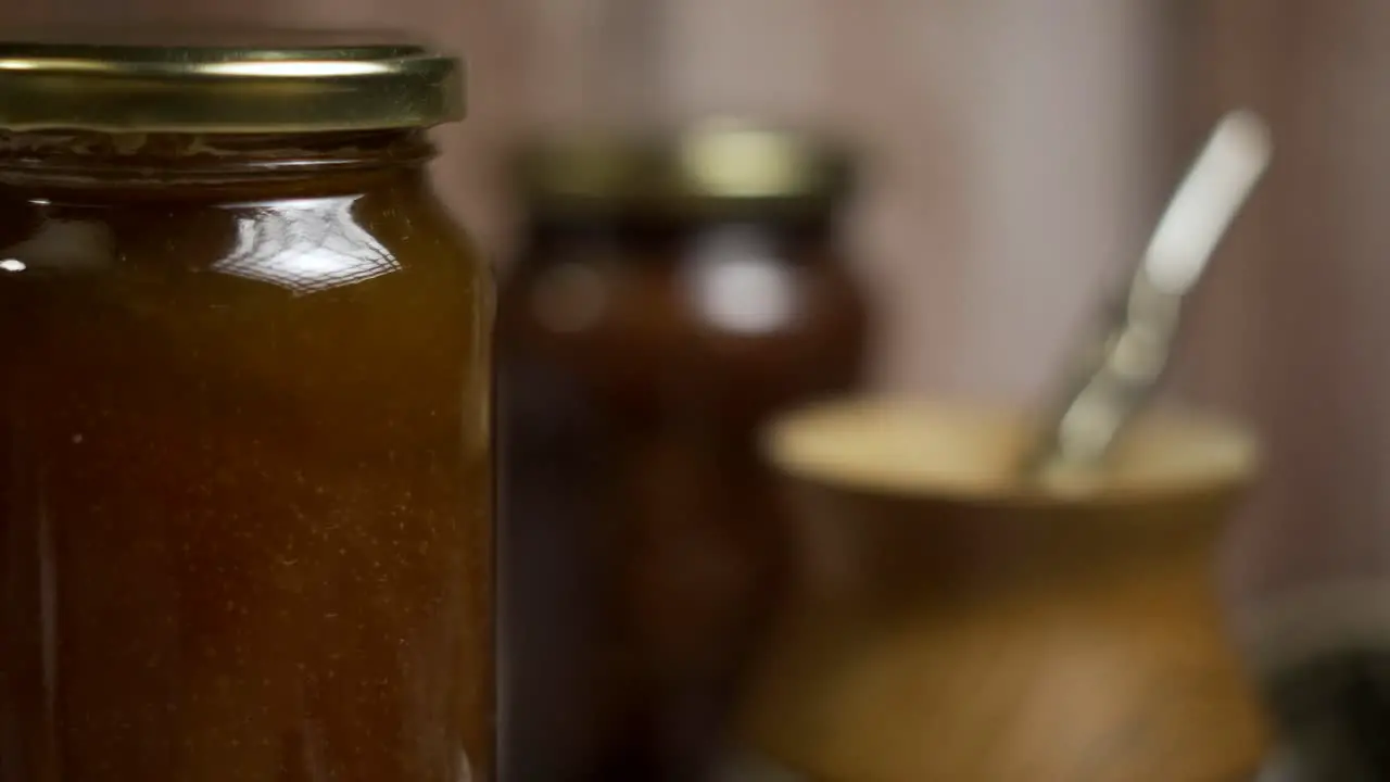 Close up of rotating mason jar of peach jam with "mate" behind