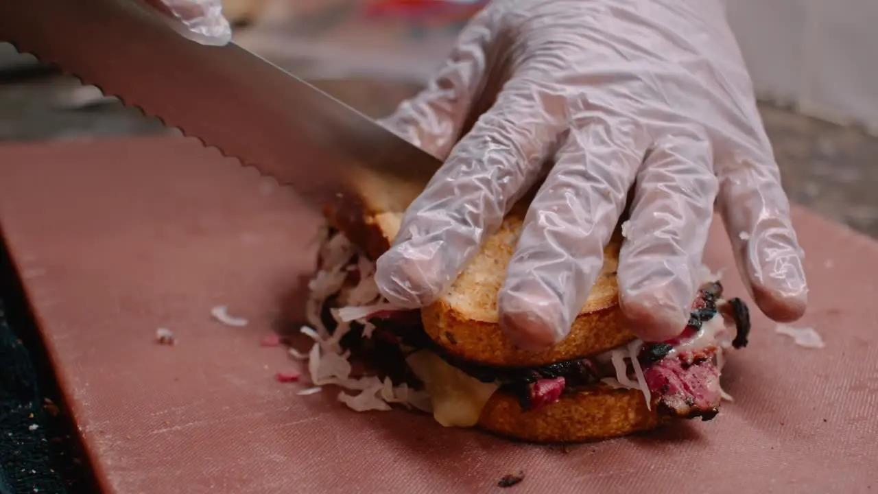 Cutting pastrami sandwich with hands in gloves medium shot