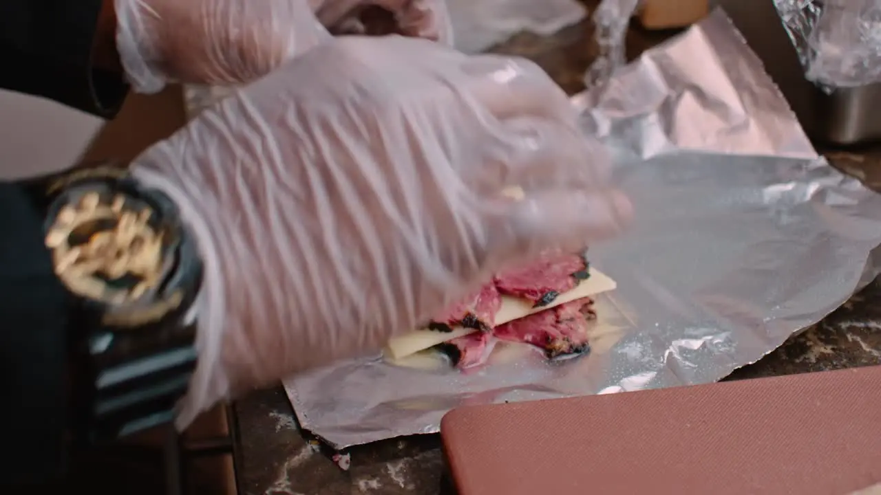 Preparing pastrami and cheese on aluminum foil close up