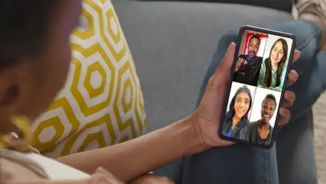 Close Up Of Woman Sitting On Sofa At Home Having Group Online Chat With Friends On Mobile Phone