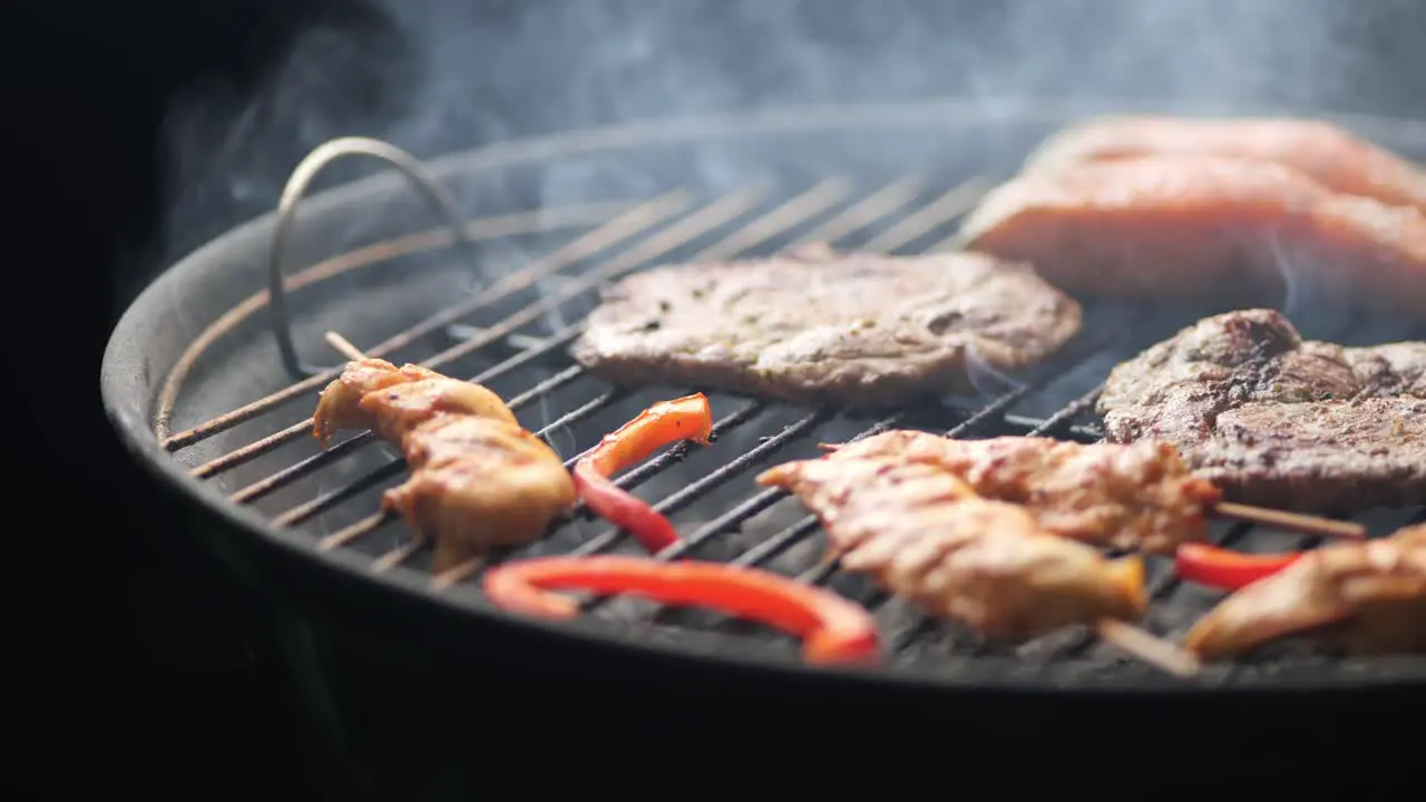 Slow motion shot of a grill with steak chicken skewers peppers and salmon