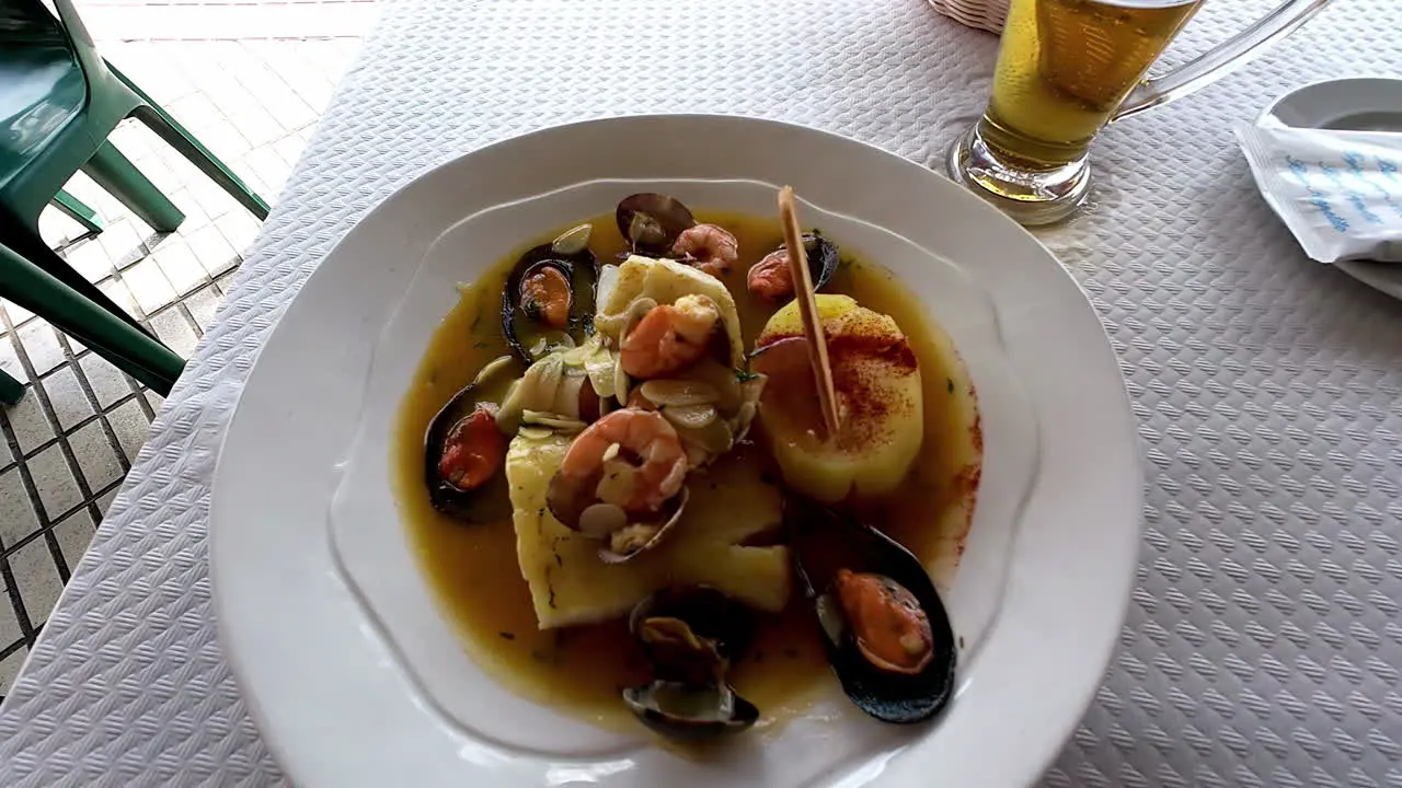 A Reveal Shot Of A Sea Cuisine And A Glass Of Drink Placed On a White Table