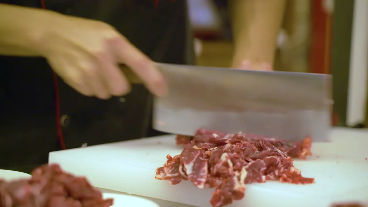 Skilled Hands of Chinese Chef Cutting Raw Beef Meat Close Up