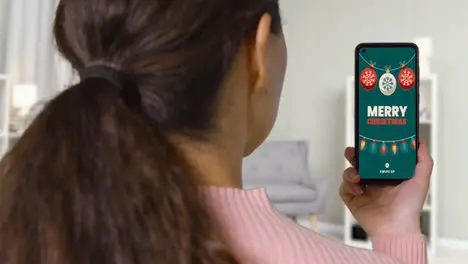 Close Up Of Woman At Home Looking At Christmas Online Offers On Mobile Phone