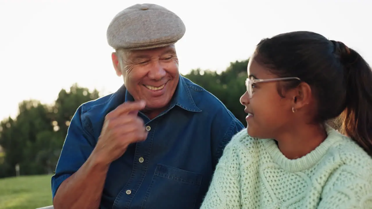 Sunrise grandfather and girl talking in park