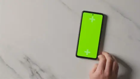 Overhead Studio Shot Of Man Using Green Screen Mobile Phone