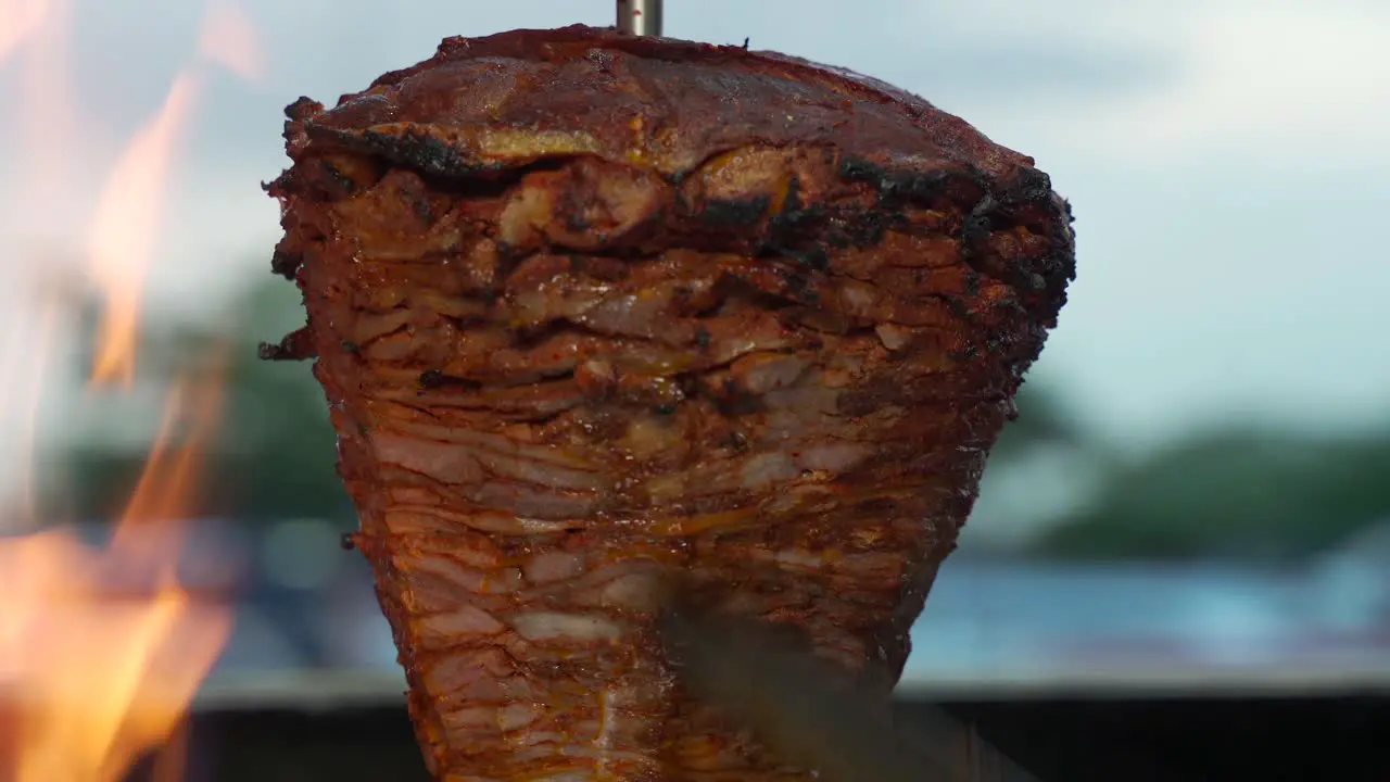 Mexican latin taquero spinning the trompo of Carne al pastor asada beef pork in a mexico restaurant cantina and preparing taco