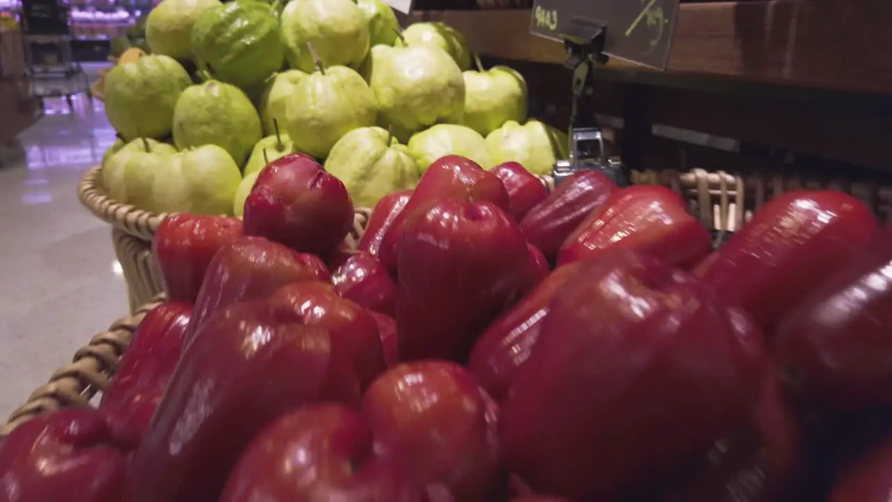 Panning camera over the fruit shelf stall in supermarket with many rose apple and guava on stall