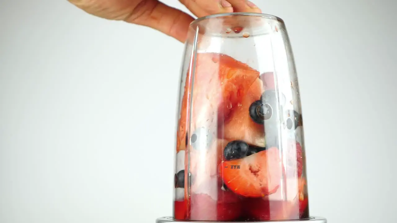 Red fruit and berries in a blender churned up to a pulp ready for a healthy smoothie